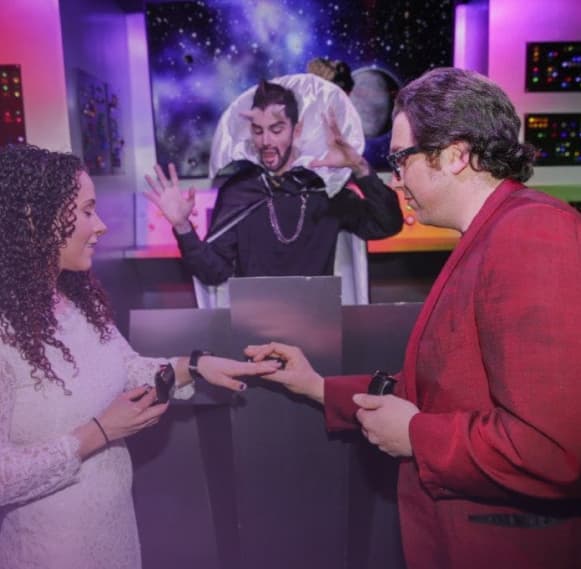 Groom putting ring on bride with character minister Spock at Sci-Fi Wedding Chapel.